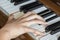 Girl\'s right hand finger holding pressed keys on a piano