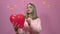 A girl is sad and holds a heart-shaped balloon in her hand and bursts it with a needle on Valentine`s Day