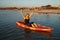 The girl is sailing on a kayak, holding an oar in her hands.