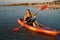 The girl is sailing on a kayak, holding an oar in her hands.