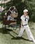 Girl in sailor suit pulling dog in basket