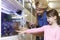 Girl With Sales Assistant Choosing Goldfish In Pet Store