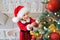 A girl in a Santa hat decorates the Christmas tree on Christmas eve and smiles sweetly in anticipation of the holiday