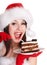 Girl in santa hat eat cake on plate.