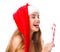 A girl in a santa hat holds a candy and looks at him.