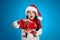 Girl in Santa hat with hourglass on light blue background. Christmas countdown