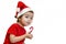 girl in a santa hat and red dress. baby eats a candy cane with appetite, looks out and looks cunningly. Christmas sweets and gift