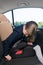 Girl in a school uniform sits in a child seat in a car and fastens his seat belt