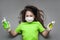 Girl schoolgirl in a medical mask in gloves holds antiseptic in her hands for disinfecting hands on a gray background. The concept