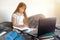 Girl schoolgirl sitting on the bed and studying, doing homework on a laptop, near books. Online home schooling, e-learning
