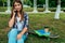 Girl schoolgirl, student 13-16 years old sitting park green grass city. In hands phone rings parents. Rest after level