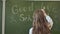 Girl schoolgirl writes on the blackboard phrase - Good bye school. Farewell to the school.