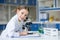 Girl scientist in lab coat writing in clipboard