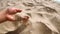 Girl scoops handful of sand in her palm scatters sand through fingers