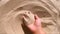 Girl scoops handful of sand in her palm scatters sand through fingers