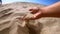 Girl scoops handful of sand in her palm scatters sand through fingers