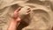 Girl scoops handful of sand in her palm scatters sand through fingers