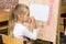 Girl scratching nose listening to teacher carefully at drawing lesson