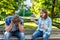 The girl screams at young man. Summer in park on a bench. The guy is crying and sad, clasping his head in his hands