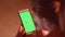 Girl scrolls smartphone with green screen and 3d tracking points