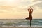 Girl on sea beach practicing yoga. Back view. Beautiful sunlight