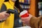 girl seller holds a barcode scanner in her hands and is counting on a man with a glass of coffee in his hand