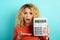Girl is shocked and shows her debt on calculator display. Cyan background