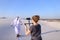 Girl shoots on camera dancing Muslim man in spacious desert on h