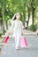 Girl with shopping bags walk in park. Little princess with crown on long blond hair. Child with paper bags in summer