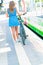 A girl in a short dress with a bicycle stands on a railway platform