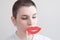 A girl with short hair tries on huge red lips. Concept of plastic surgery. Concept of modern fashion big lips. Bald