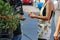 Girl in short jumper dress and boy with long hair and tee shirt pay vendor by flowers at farmers market - unrecognizable and selec