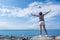 Girl in shorts and striped t-shirt holds her hands to the sides and escorts of airplane departing over the sea beach