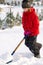 Girl shoveling snow on home drive way. Beautiful snowy garden or front yard. Teenager removing snow with a shovel in the