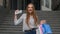 Girl showing Black Friday inscription from shopping bags, looking satisfied with low prices. Outdoor