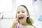 Girl showing her healthy milk teeth at dental office