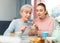 Girl showing pictures on smartphone to interested elderly mother