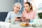 Girl showing pictures on smartphone to interested elderly mother