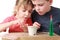 Girl shows brother how to sow grains in pot