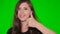 Girl shows a gesture thumb up isolated on a green screen. Close-up face of a young smiling woman on chromakey background