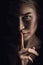 Girl shows a sign of silence. Face on a dark background. Dont Talk Concept