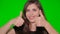 Girl shows two hands gesture thumb up isolated on a green screen. Close-up face of a young smiling woman on chromakey background