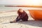 A girl sideways near a red boat on the beach by the sea