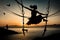 A girl in silhouette enjoying the sunset in swing