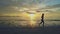 Girl silhouette walks slowly along wet beach at dawn