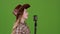 Girl sings into a retro country music microphone. Green screen. Slow motion. Side view