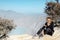 Girl sit on rock above volcano Kawah Ijen acid lake