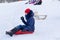 Girl sit on sled with blue jacket, camera in hand