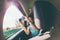 A girl sits in the back seat of a car and takes a photo of a passing landscape from a window