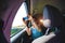 A girl sits in the back seat of a car and takes a photo of a passing landscape from a window